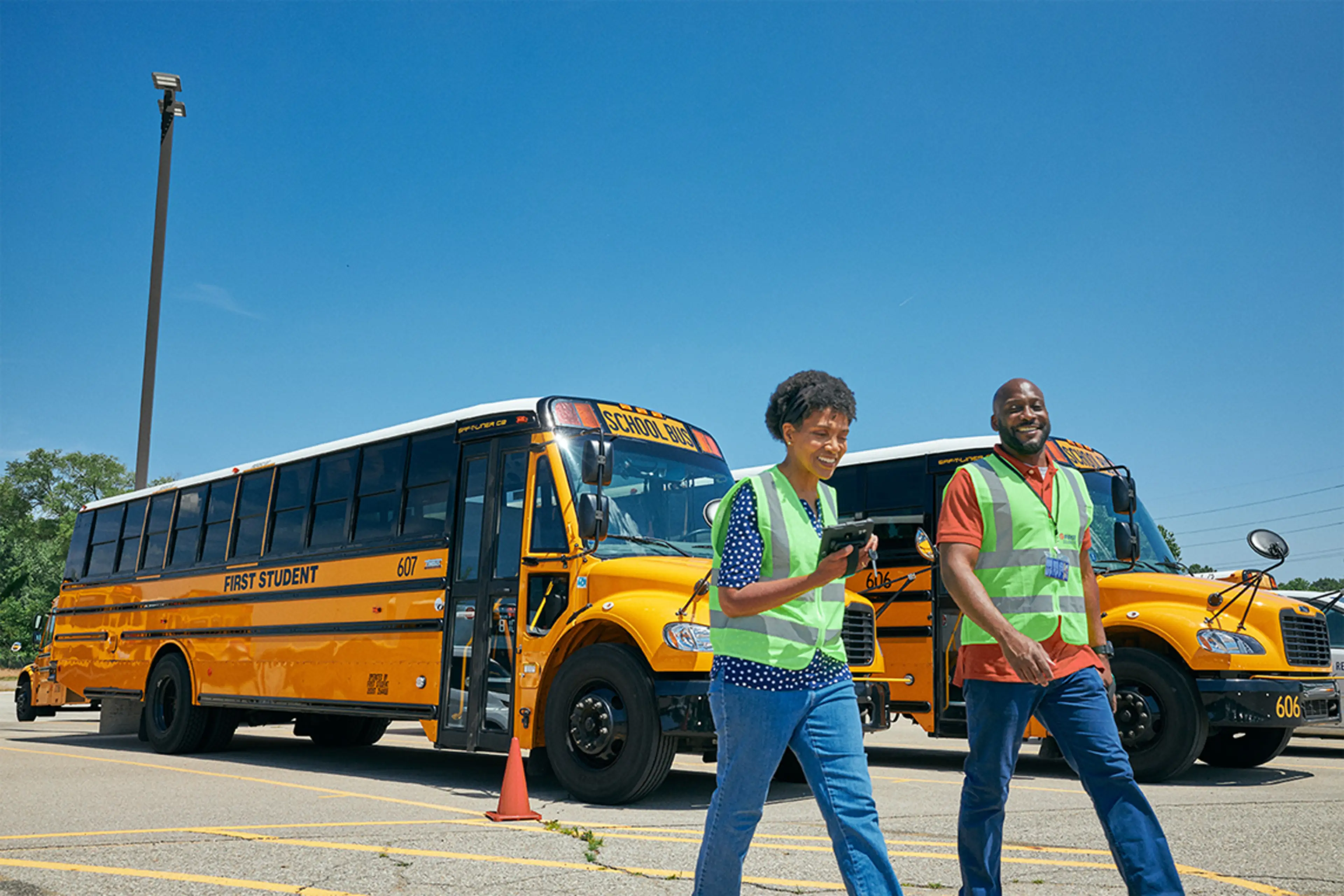 Two staff members walking away from parked school busses.
